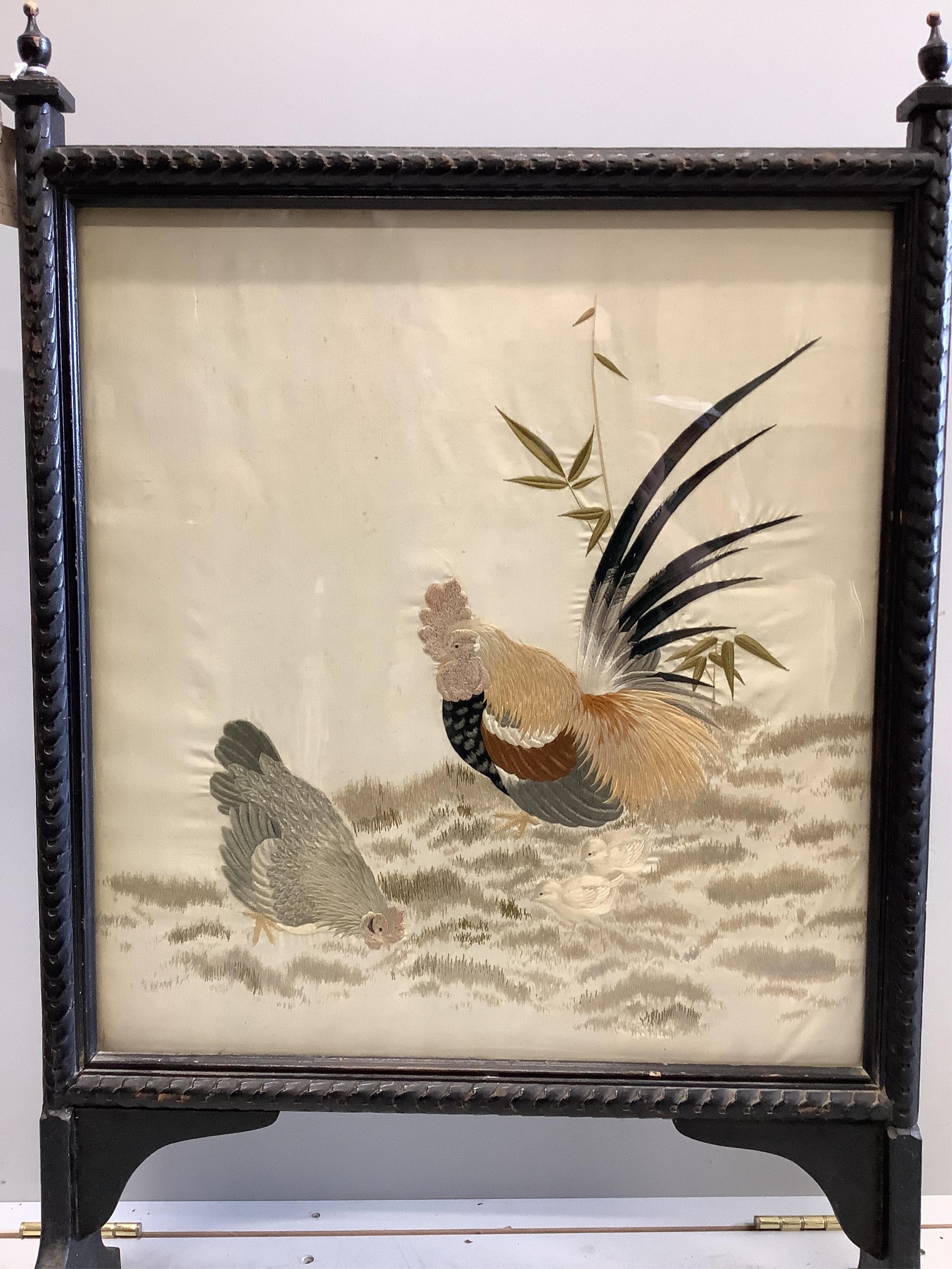 A Victorian fire screen inset with a Japanese cream silk embroidered panel of a cockerel, hen and two chicks, beautifully embroidered with rows of couched silk on the bodies of all the birds, their feathers and faces inc